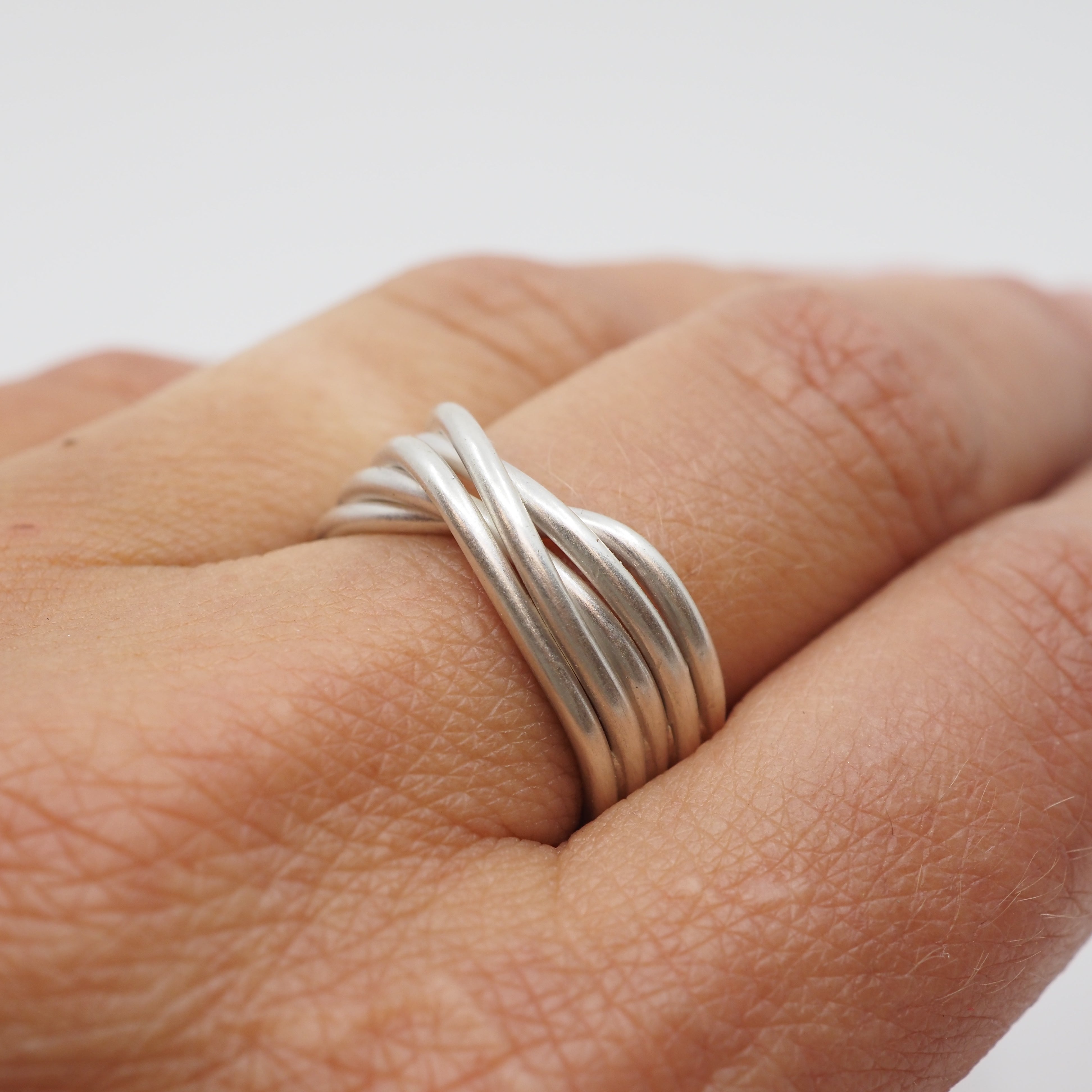 Silver ring on a person's finger against a plain background