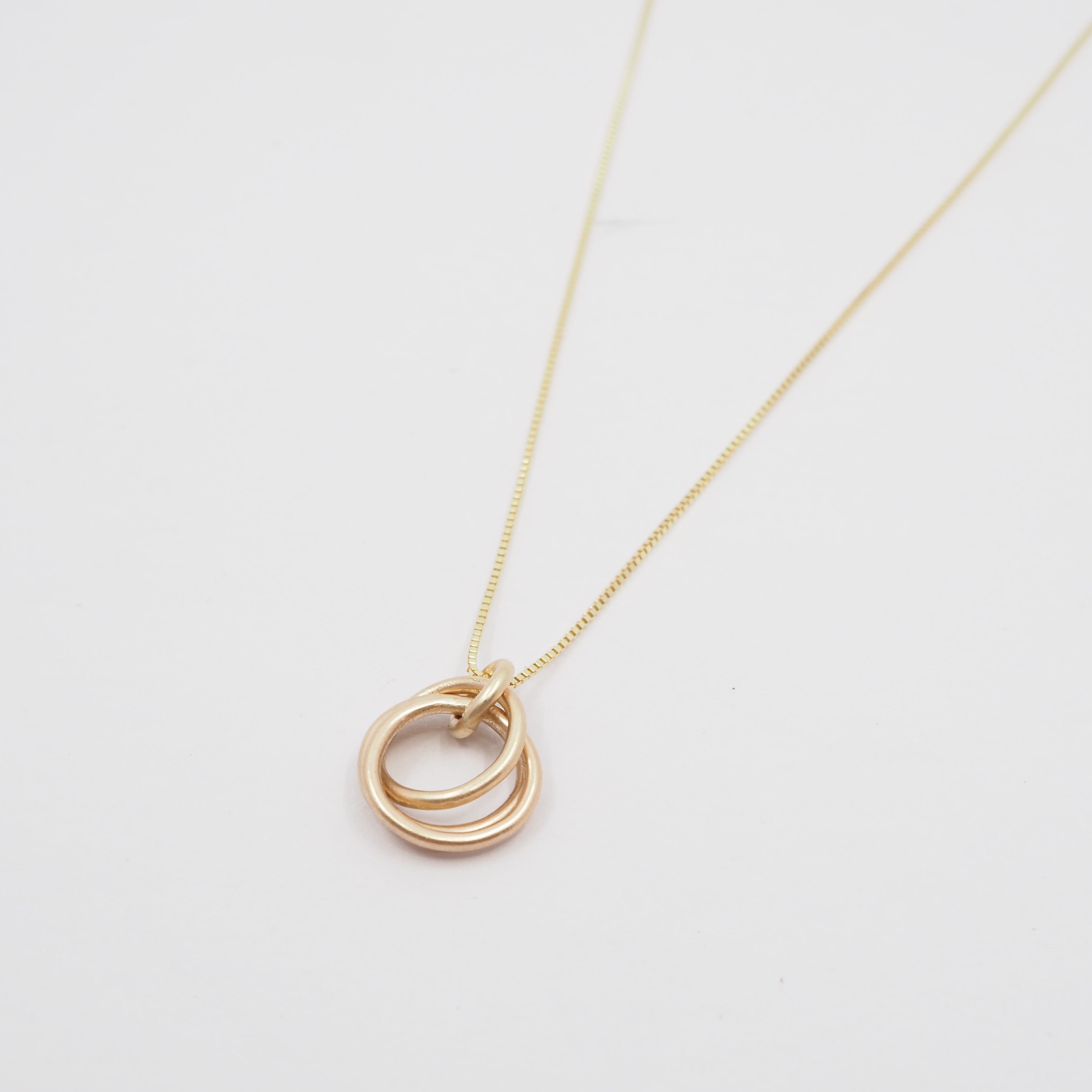 Gold necklace with interlocking rings on a light gray background