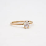 Gold ring with a clear gemstone on a light beige background