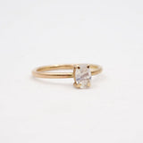 Gold ring with a clear gemstone on a light beige background