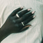 A close-up of a hand resting on a wrinkled white fabric, wearing two silver rings.