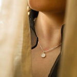 close up of woman wearing a silver zodiac pendant necklace