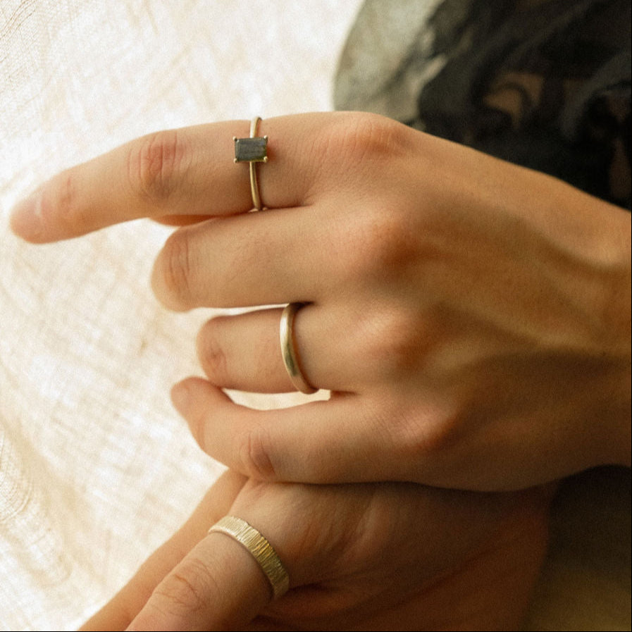 Close-up of hands wearing silver rings on a textured fabric background