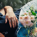 Person holding a bouquet of flowers with a close-up of a hand wearing a ring.