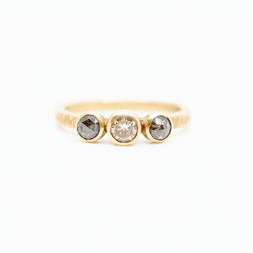 A gold diamond ring with bezel setting, featuring a central champagne diamond and two side diamonds.