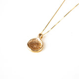 A 10K gold necklace with a carved pendant on a gold chain, displayed against a white background.