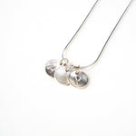 Silver necklace with two round pendants with letters on a white background