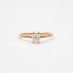 Gold ring with a white gemstone on a light beige background