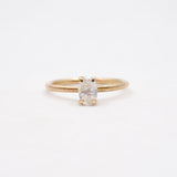 Gold ring with a white gemstone on a light beige background