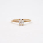 Gold ring with a white gemstone on a light beige background