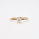 Gold ring with a white gemstone on a light beige background