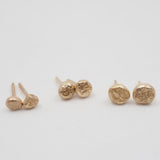 Set of gold stud earrings on a light gray background