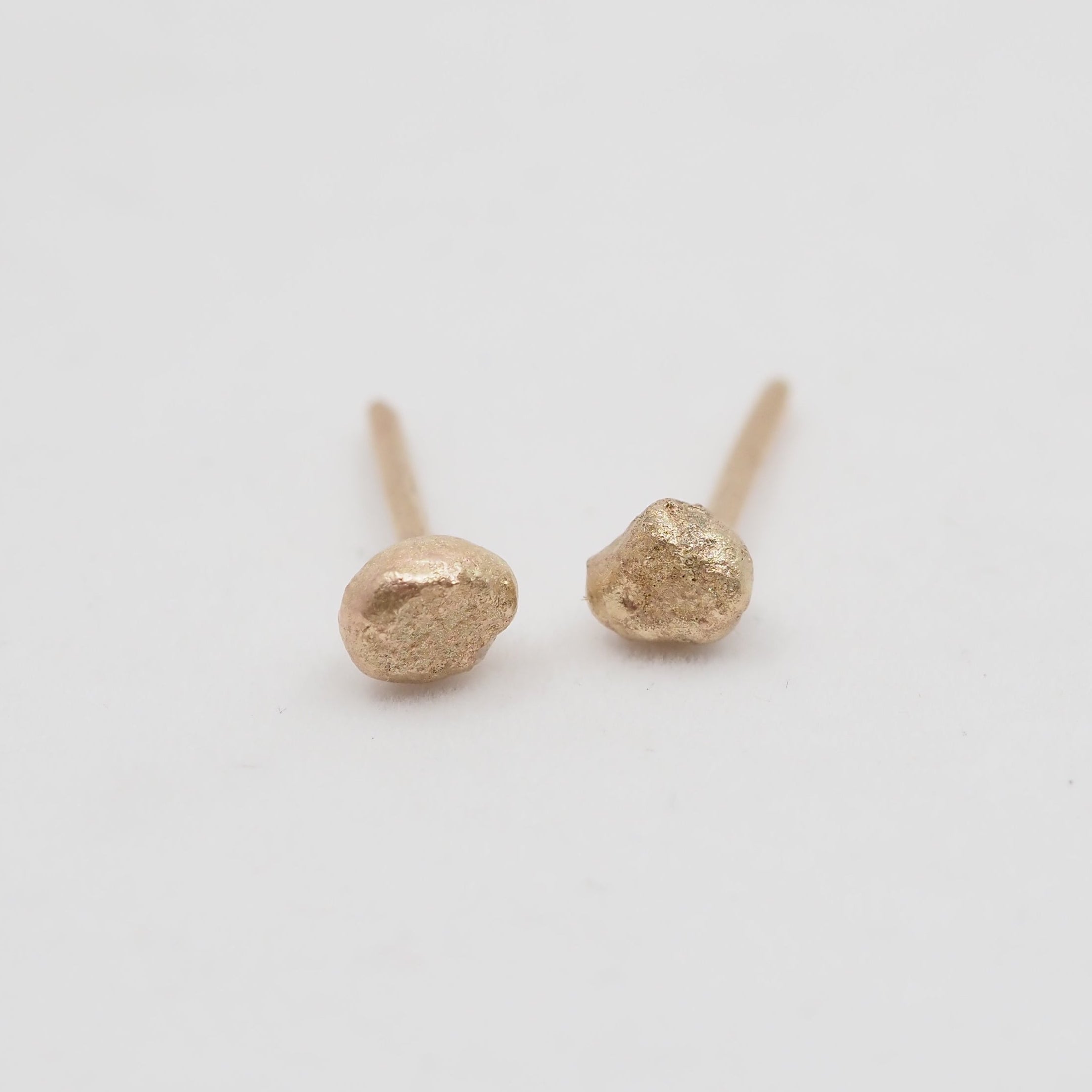 Gold stud earrings on a light gray background