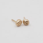 Gold stud earrings on a light gray background