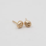 Gold stud earrings on a light gray background