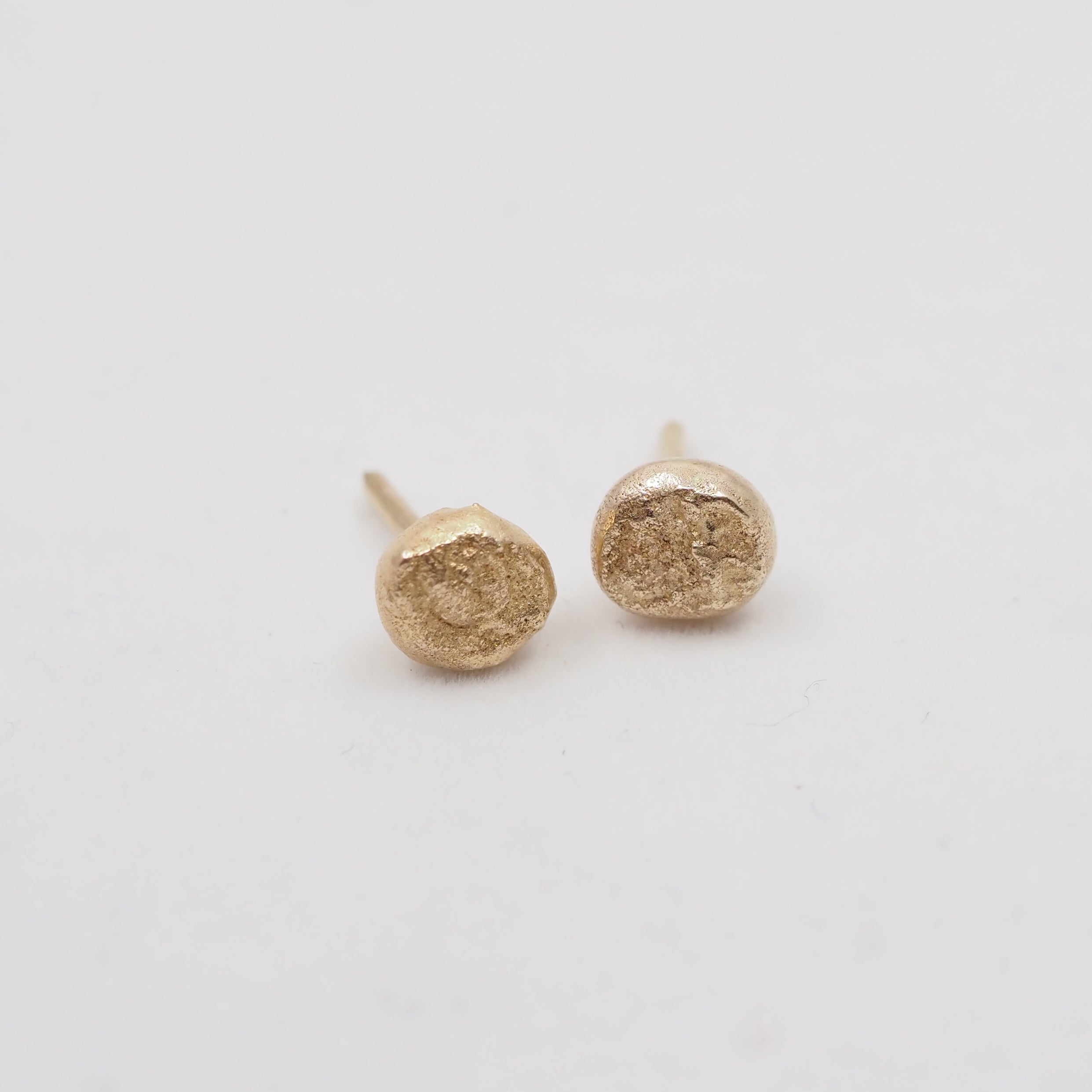 Gold round earrings on a light gray background