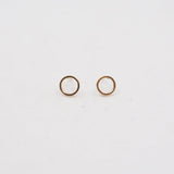 Two gold circle earring studs on a light gray background