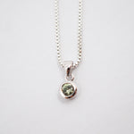 A silver box chain necklace with a small round bezel-set green gemstone pendant, shown against a plain white background.