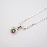 A silver box chain necklace with a small round bezel-set green gemstone pendant, shown on a plain white background.