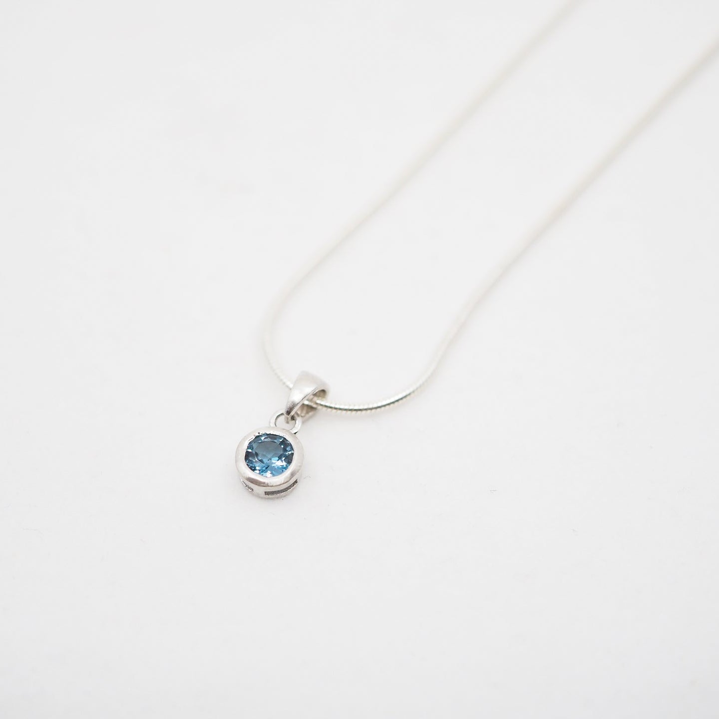Necklace with a blue gemstone pendant on a white background