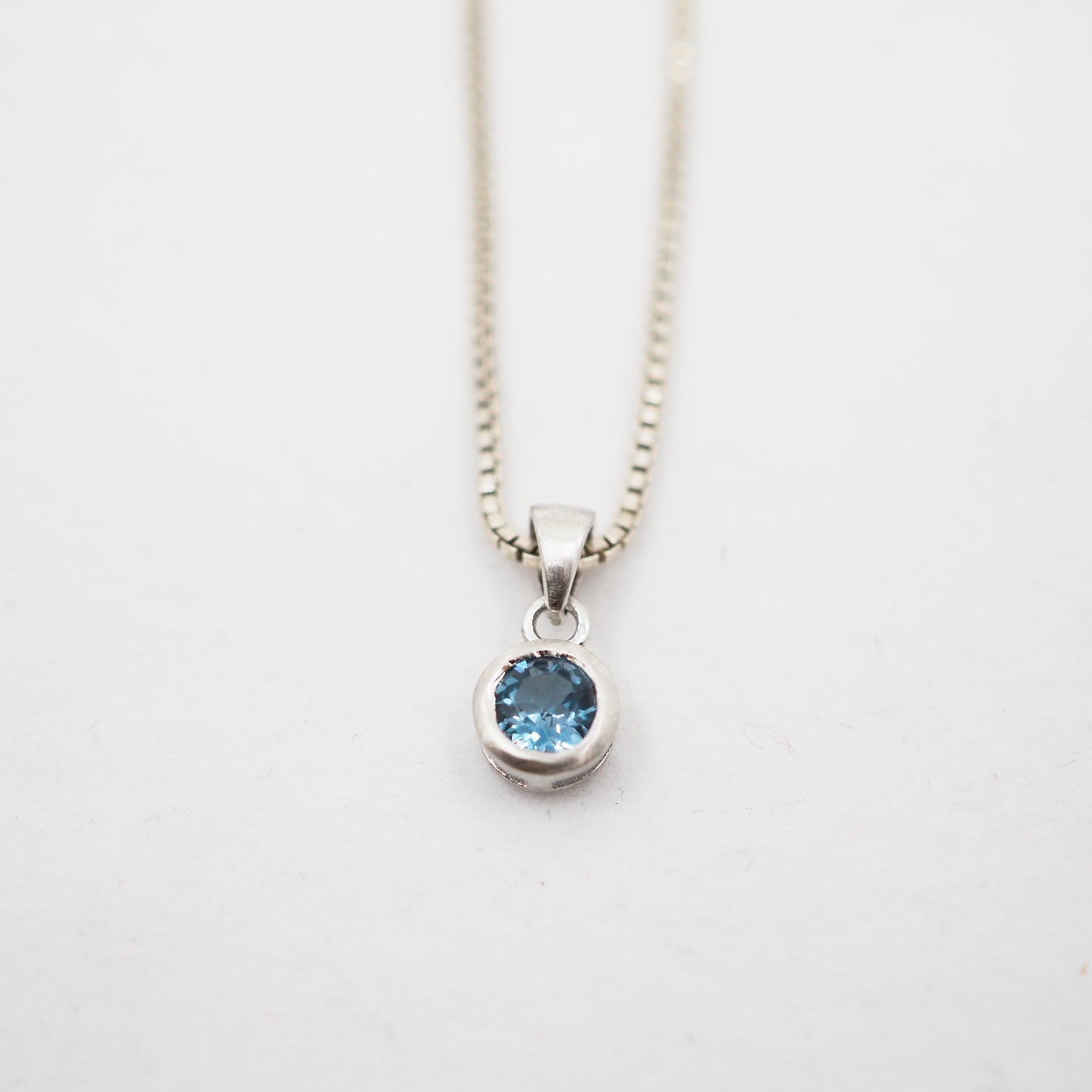 Necklace with a blue gemstone pendant on a white background