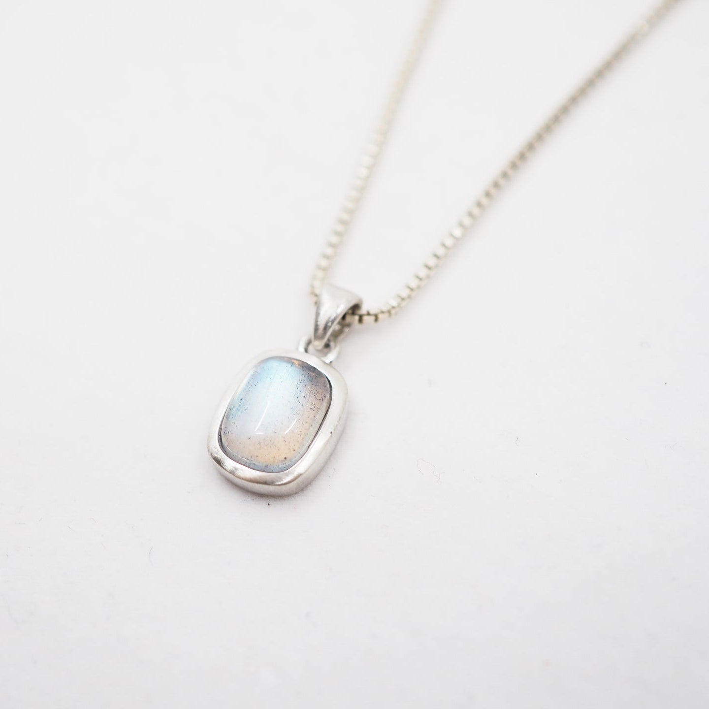Necklace with a pendant featuring a rainbow labradorite stone on a light gray background