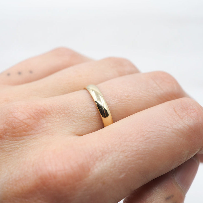 Gold ring on a person's finger against a light background