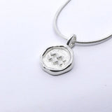 A silver-colored necklace with a round pendant featuring a zodiac sign symbol, attached to a chain.