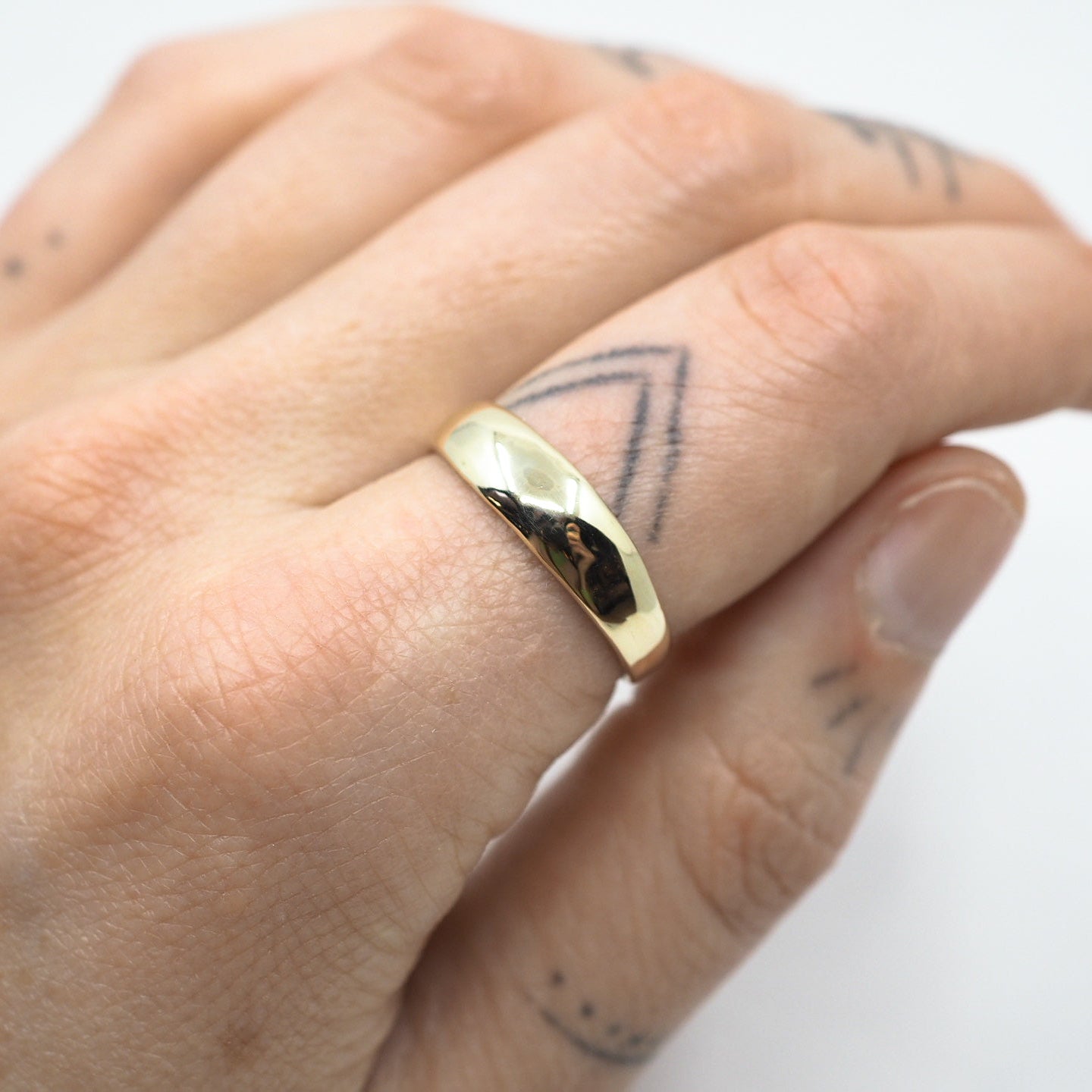 Gold ring on a hand with a white background
