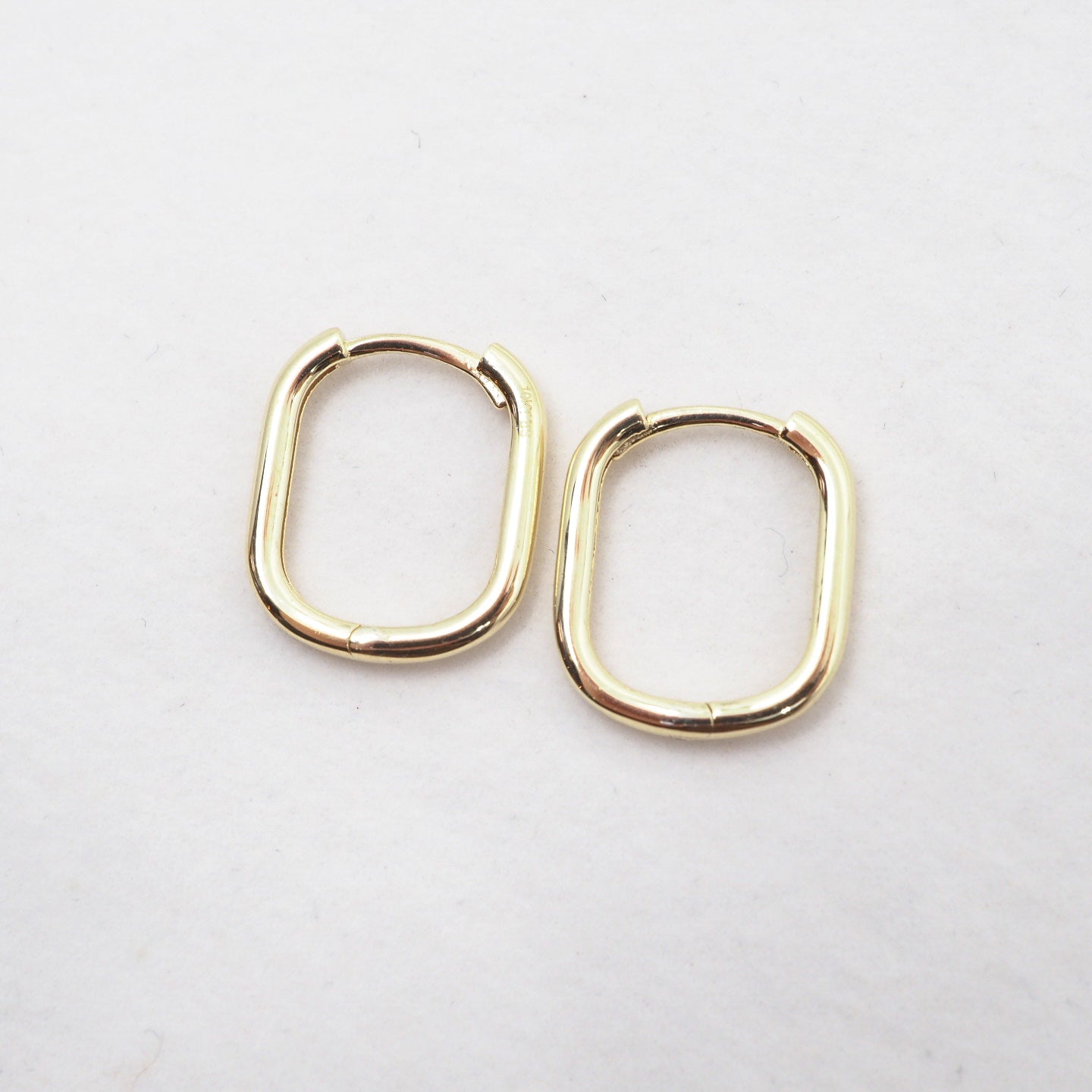 Gold hoop earrings on a light gray background