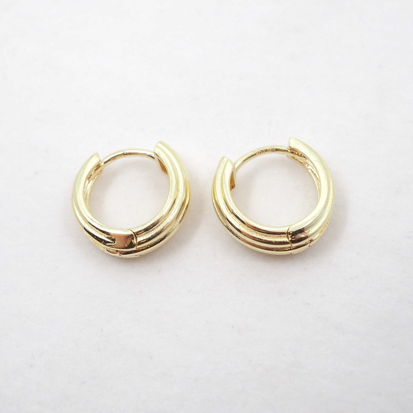 Pair of gold hoop earrings on a light gray background