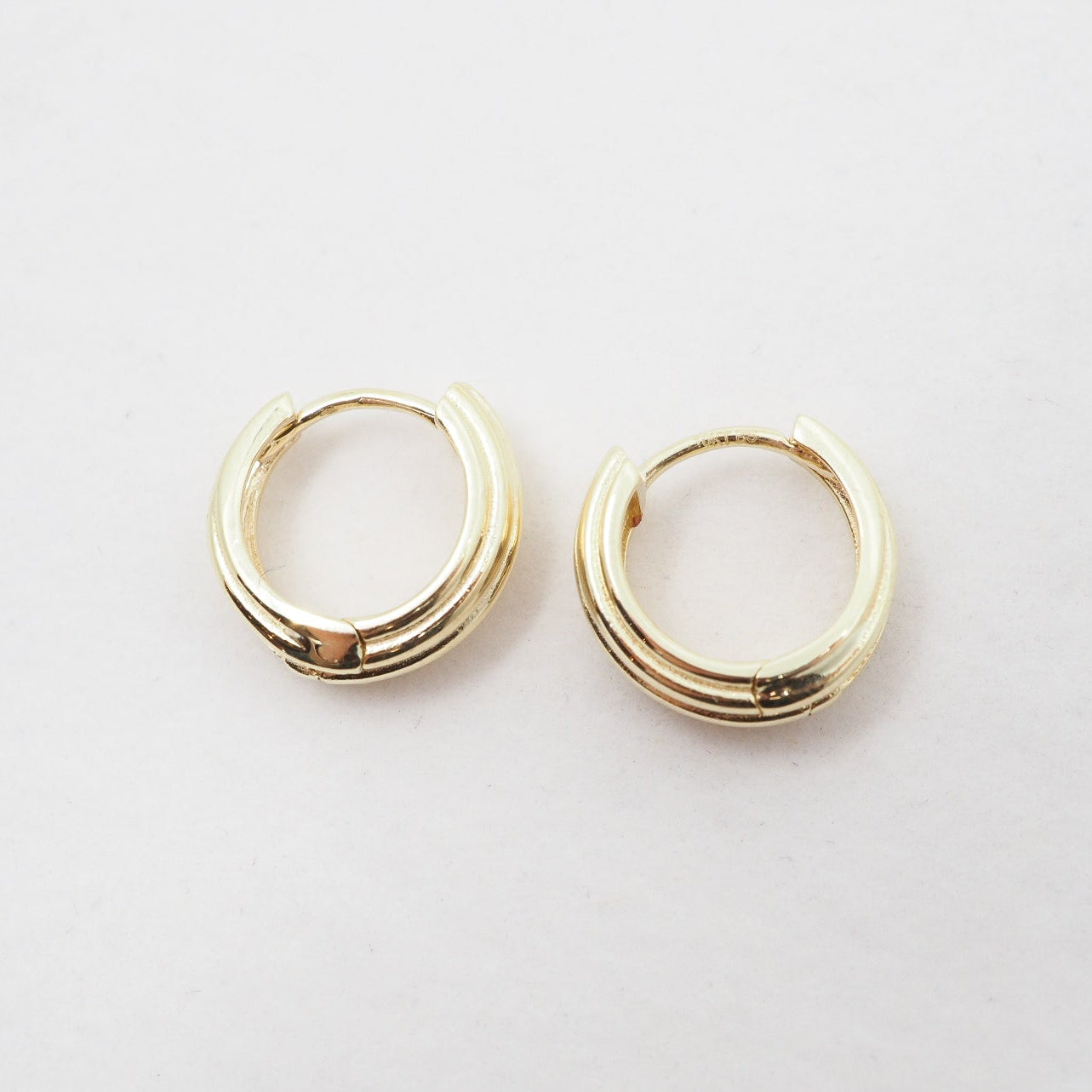 Gold hoop earrings on a light gray background