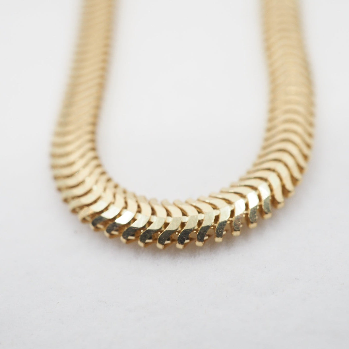 Gold snake chain on a light gray background