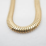Gold snake chain on a light gray background