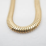 Gold snake chain on a light gray background