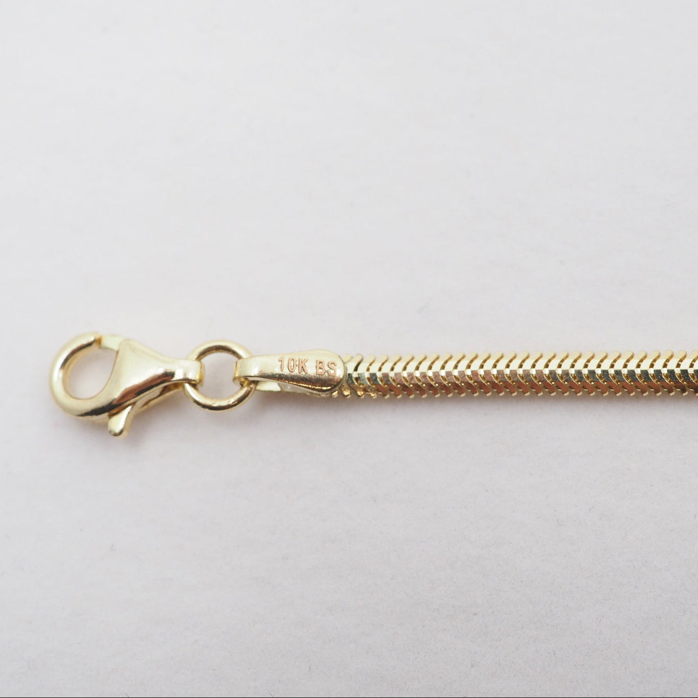 Gold chain necklace with clasp on a light gray background