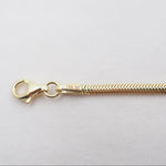 Gold chain necklace with clasp on a light gray background