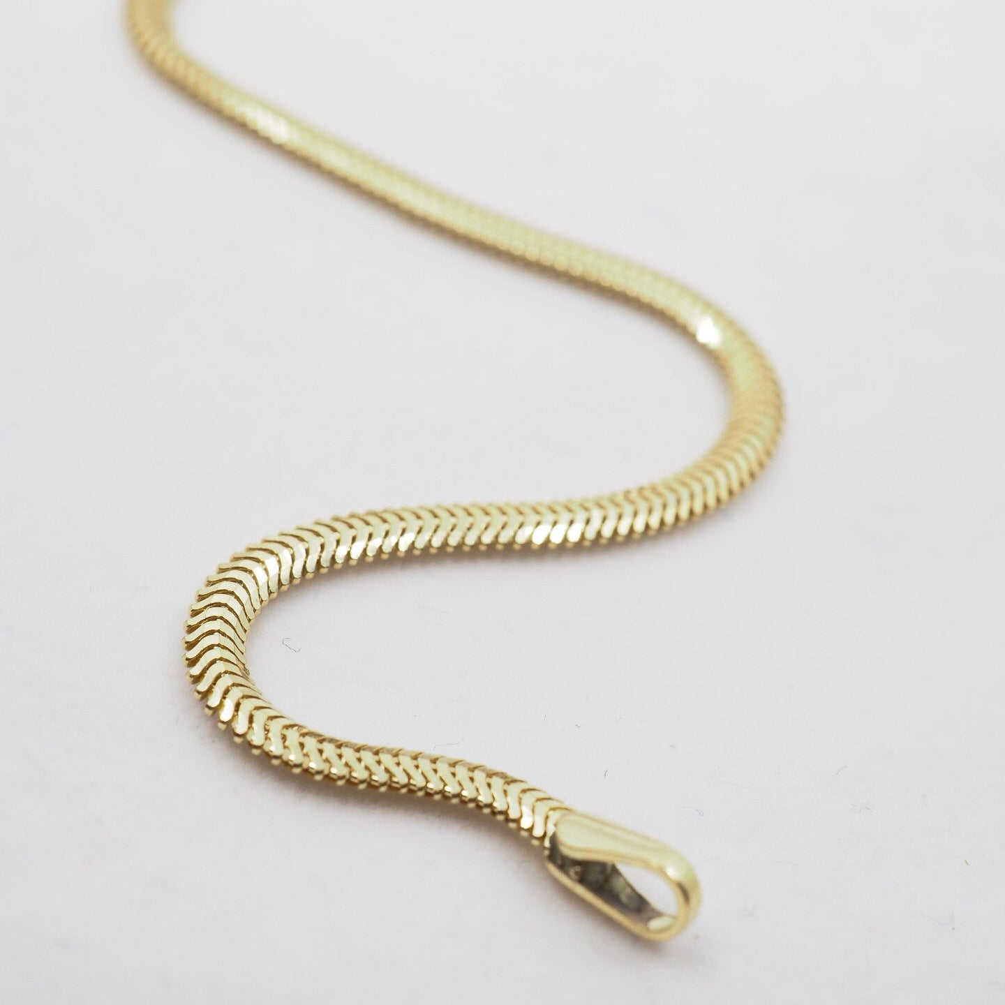 Gold chain bracelet on a light gray background