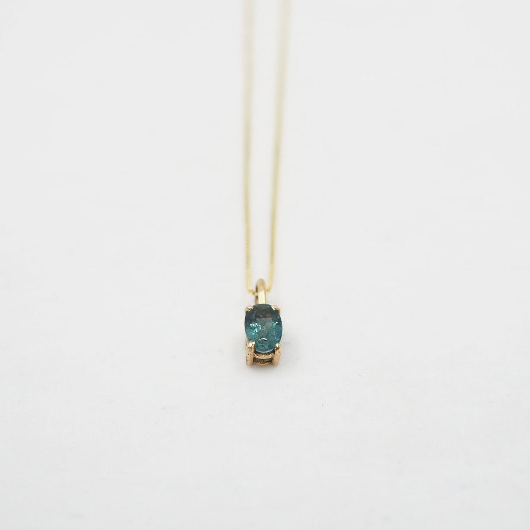 Necklace with a green gemstone pendant on a white background