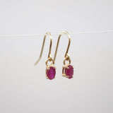 Gold earrings with red gemstones on a white background