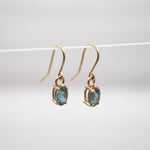 Gold earrings with green gemstones on a white background