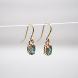 Gold earrings with green gemstones on a white background