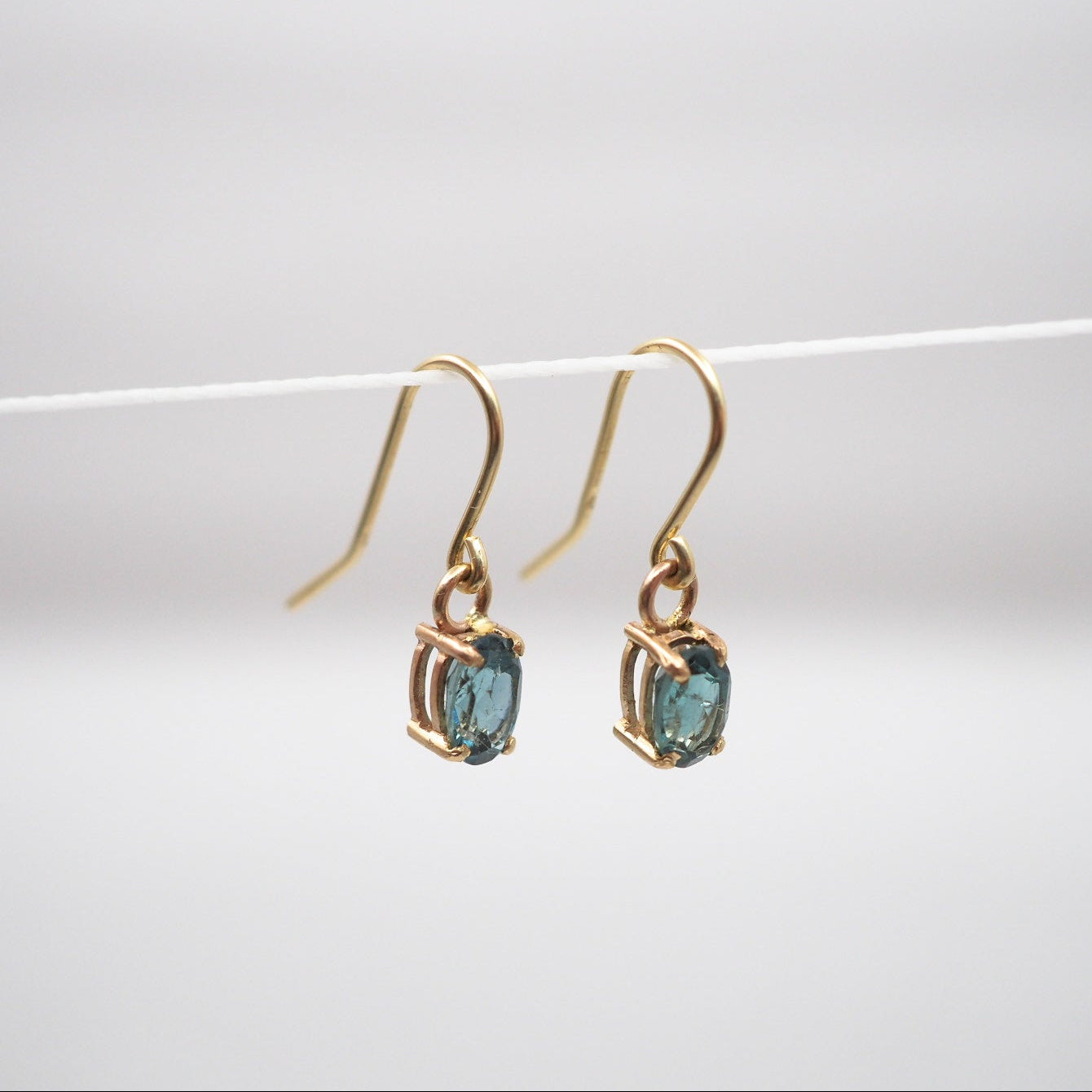 Gold earrings with blue gemstones on a white background