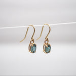 Gold earrings with blue gemstones on a white background