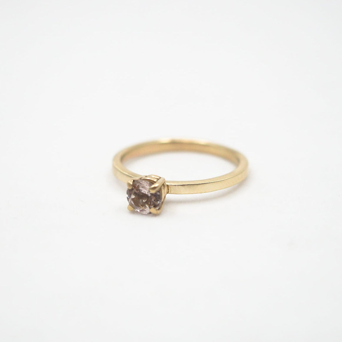 Gold ring with a pink gemstone on a white background