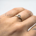 Hand wearing a gold ring with a morganite on a white background