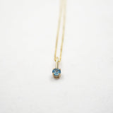 Gold necklace with a blue gemstone pendant on a white background