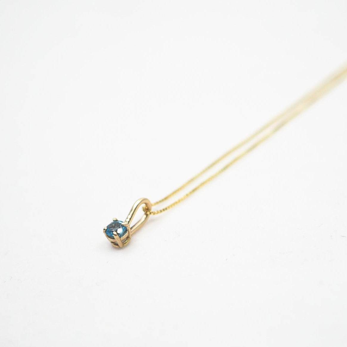 Gold necklace with a small pendant on a white background