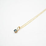 Gold necklace with a small pendant on a white background