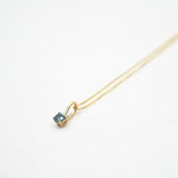 Gold necklace with a small pendant on a white background